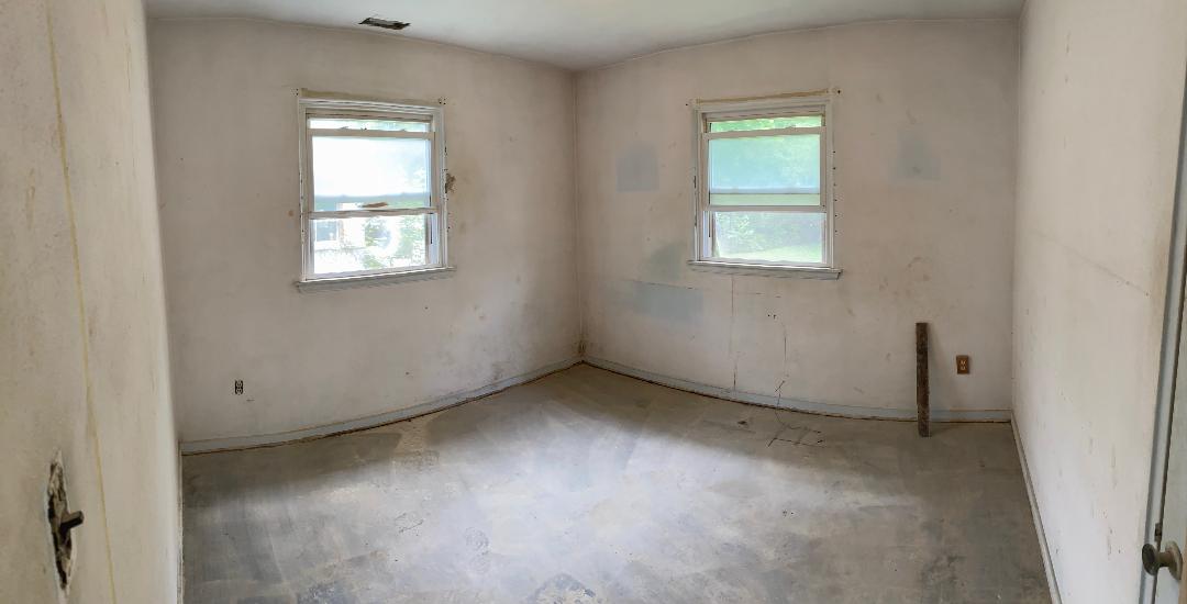 Bedroom before renovation with damaged walls and flooring removed at 2155 N Catherwood
